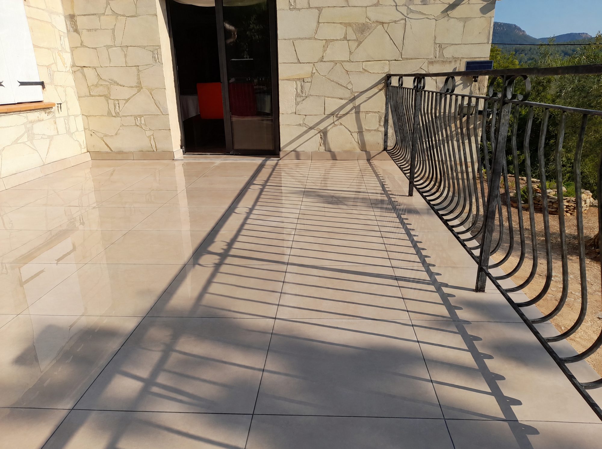 Terrasse extérieure carrelée avec garde-corps en fer forgé