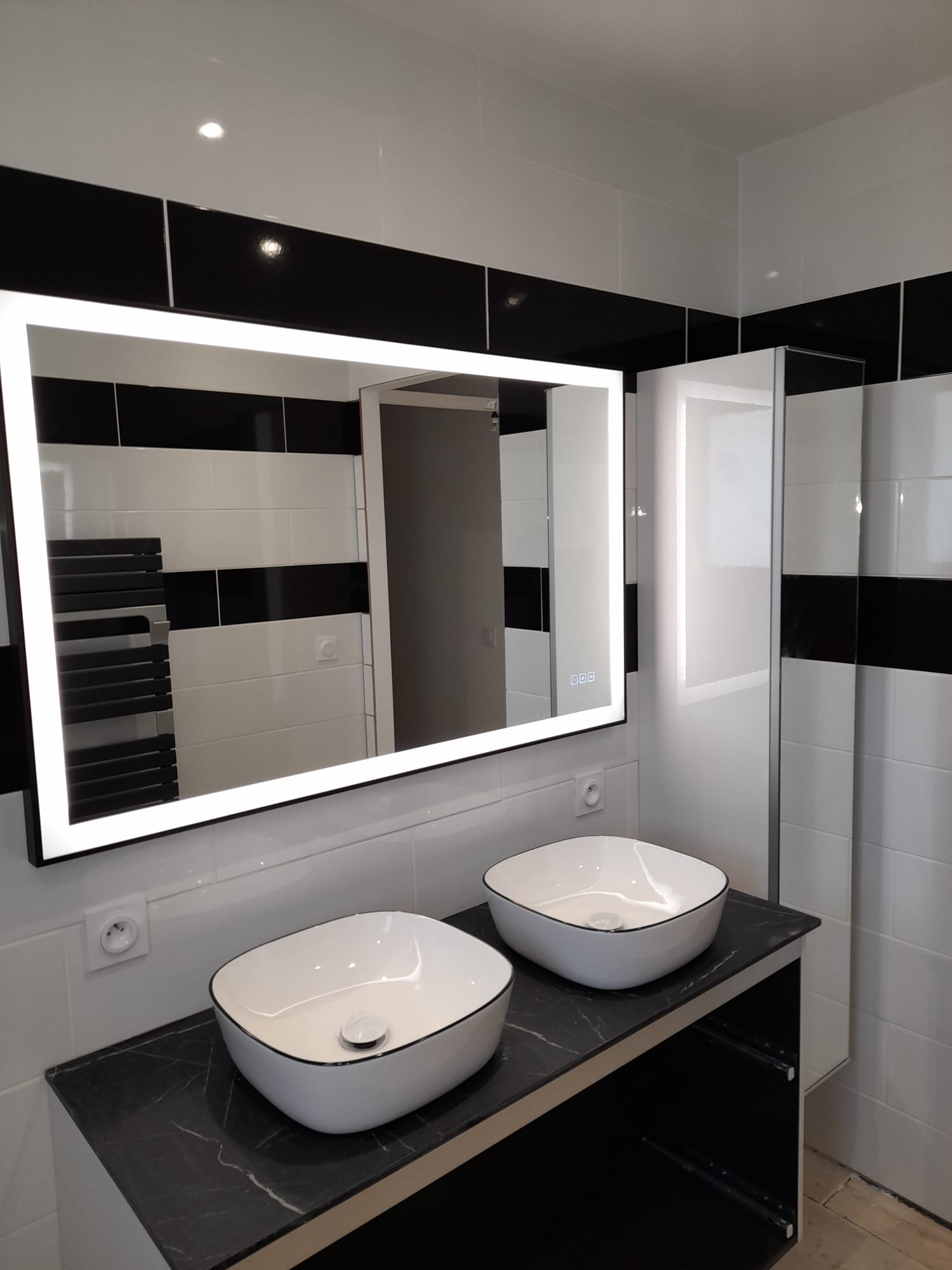 Meuble double vasque et miroir lumineux dans une salle de bain rénovée