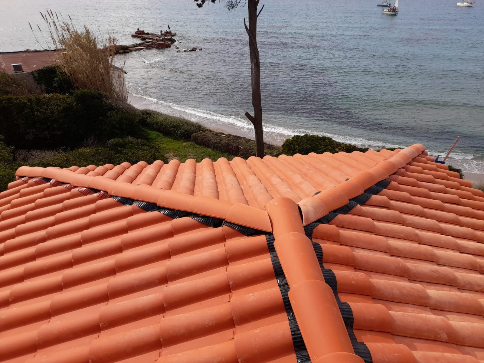 Toiture en tuiles rondes refaite par l'entreprise, face à la mer